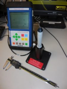 A meter and a scle kept on a table with a monitor in front